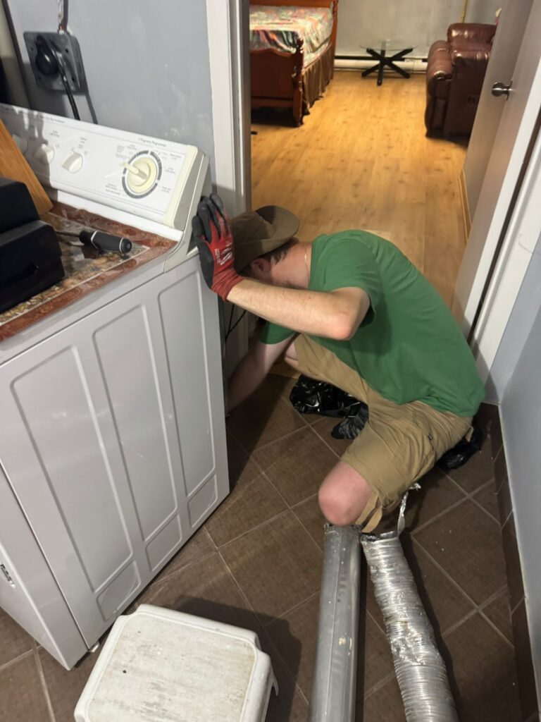 Technician accessing dryer vent connection during duct cleaning service — Toronto