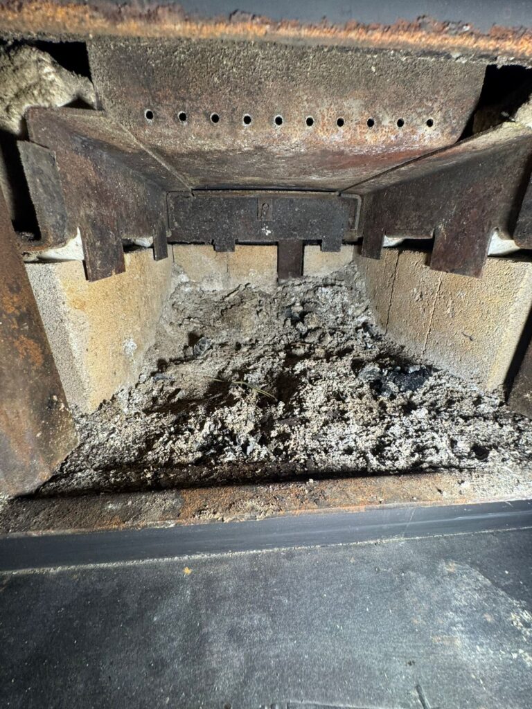 Wood stove firebox interior showing ash buildup and wear — WETT inspection finding